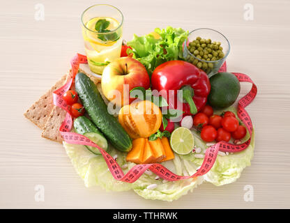 La frutta e la verdura fresca con nastro di misurazione su sfondo di legno Foto Stock