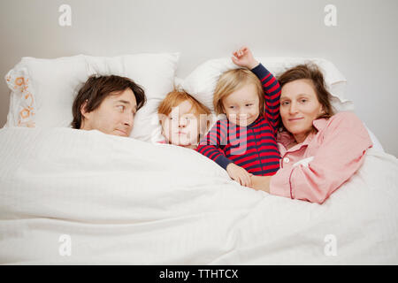 La famiglia felice sdraiato sul letto di casa Foto Stock