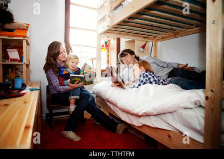 I genitori che mostra foto libro per bambini in camera da letto a casa Foto Stock