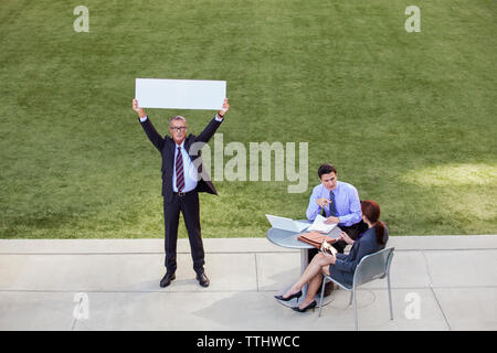 uomo d'affari che mostra il grafico mentre si trova accanto ai colleghi Foto Stock