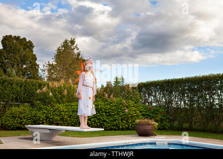 Ragazza in costume di fata in piedi sul trampolino contro sky Foto Stock