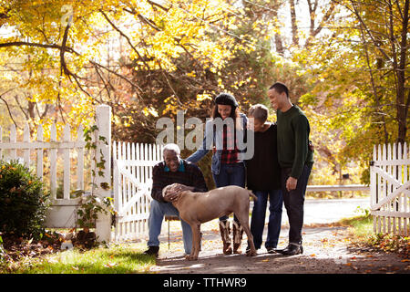 Senior man stroking cane dalla famiglia al cortile Foto Stock