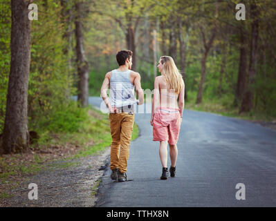 Vista posteriore del giovane a parlare mentre si cammina sulla strada Foto Stock