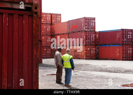 I colleghi parlare mentre in piedi da contenitori di carico al dock commerciale Foto Stock