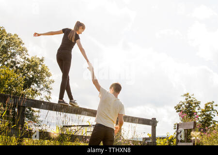 Man mano tesa della donna che cammina sulla staccionata in fattoria Foto Stock