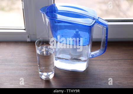 Il filtro dell'acqua brocca e un bicchiere sul davanzale di legno Foto Stock