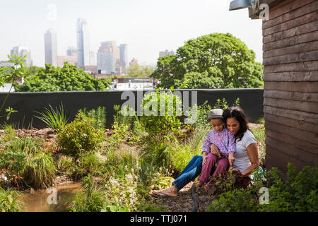 Madre seduta con il figlio a backyard Foto Stock