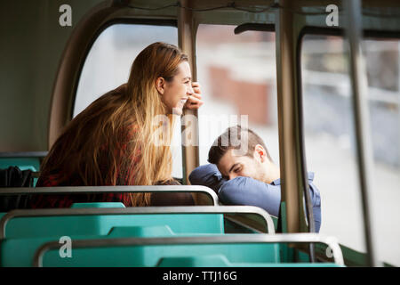 Donna felice guardando attraverso la finestra mentre l'uomo è appoggiata sul tram Foto Stock