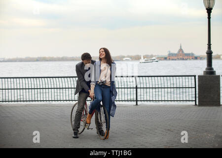 Giovane con la bicicletta sulla promenade contro il fiume Hudson Foto Stock