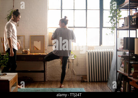 Donna fare yoga da uomo a casa Foto Stock