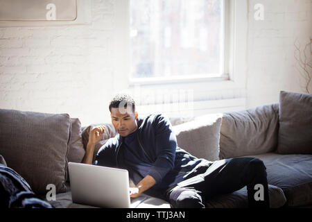 Uomo con notebook comodamente seduti sul divano di casa Foto Stock