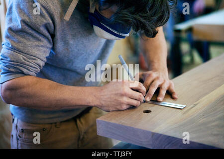 Falegname maschio marcatura sul tavolato in legno in officina Foto Stock
