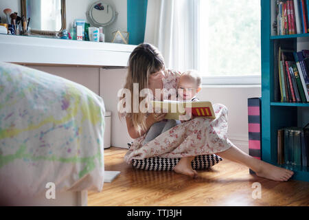Madre libro di lettura con allegro Bambino seduti sul pavimento Foto Stock