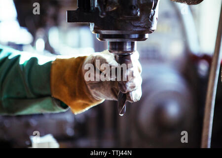 Immagine ritagliata di lavoratore regolare trapano in officina Foto Stock