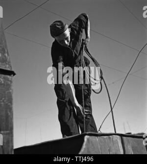 Spazzacamino. Un uomo lavora come spazzacamino e salendo sul tetto tutti vestiti per lavoro e portando la sua attrezzatura. La Svezia 1940. Kristoffersson ref 154-6 Foto Stock