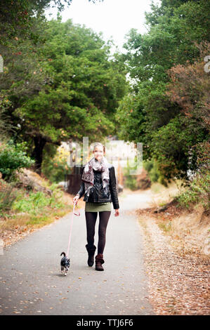 Ritratto di donna con il cane a camminare sulla strada Foto Stock