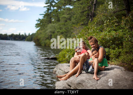 Ritratto di famiglia seduti sulla roccia dal lago Foto Stock