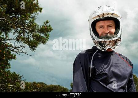 Ritratto di uomo che indossa un casco contro il cielo nuvoloso Foto Stock