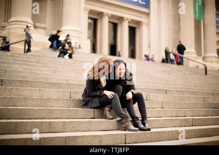 Gli amici di ridere mentre posa sui gradini Foto Stock