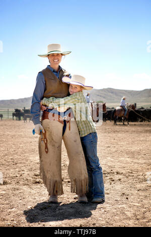 Ritratto di ragazzo abbracciando la madre mentre in piedi in ranch Foto Stock