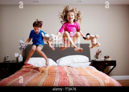 Giocoso i bambini di saltare sul letto di casa Foto Stock