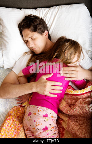 Vista aerea del padre a letto con la figlia sul letto di casa Foto Stock