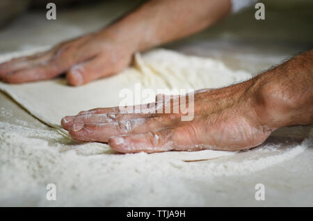 Immagine ritagliata di mani rendendo il pane pizza Foto Stock