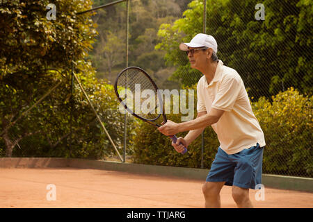 Senior uomo giocando a tennis a corte Foto Stock