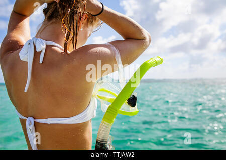 Donna con snorkel in piedi in mare contro il cielo nuvoloso Foto Stock