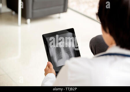 Vista posteriore dei medici cercando x-ray report nel computer tablet Foto Stock