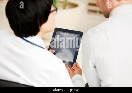 I medici cercando x-ray report nel computer tablet Foto Stock