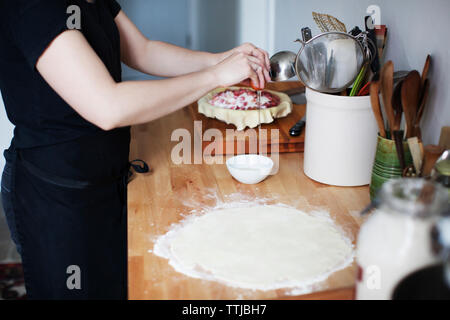 Sezione mediana della donna la rottura delle uova nel recipiente Foto Stock