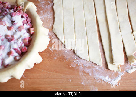 Angolo di alta vista di impasto a fette di rabarbaro nel contenitore sul bancone cucina Foto Stock