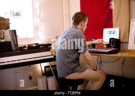 Vista laterale dell'uomo con il piano utilizzando il computer portatile Foto Stock