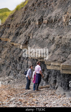 I turisti a piedi scogliere instabili a Kimmeridge Bay Dorset, England, Regno Unito Foto Stock