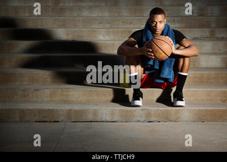 Ritratto di atleta con basket seduti sui gradini Foto Stock