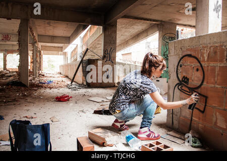 Donna graffiti di spruzzatura sulla parete edilizia Foto Stock