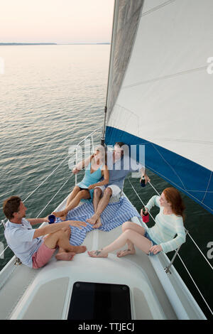 Uomo che indossa gli occhiali da sole che guarda lontano mentre è seduto su yacht contro il cielo chiaro Foto Stock