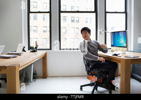 uomo d'affari che guarda alle spalle mentre lavora in ufficio Foto Stock