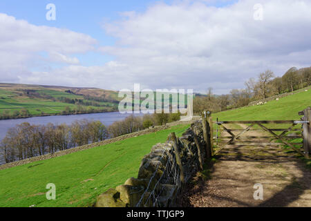 Un cancello di legno che si trova alla fine di una corsia di campagna vicino ad un campo e Gouthwaite Reservoir, Nidderdale, North Yorkshire, Inghilterra, Regno Unito. Foto Stock