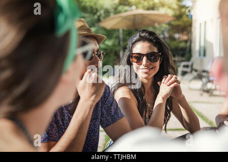 Gli amici sorseggiando seduti in cortile Foto Stock