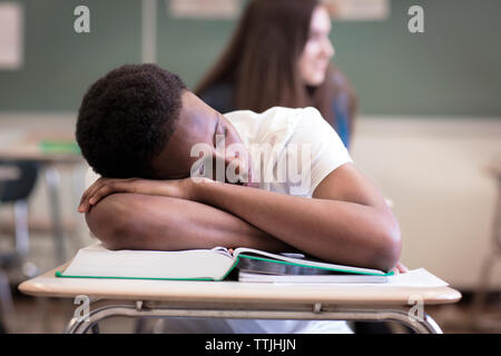 Ragazzo adolescente dormire durante la lezione in aula Foto Stock