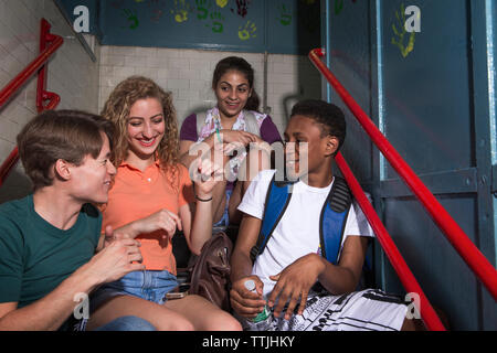 Felice amico seduto sui gradini in edificio scolastico Foto Stock