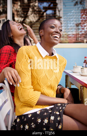 Allegro amici seduti al cafè sul marciapiede Foto Stock