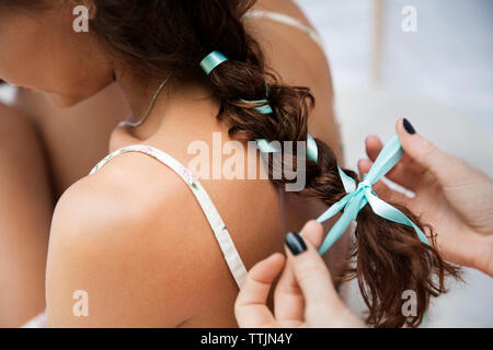 Immagine ritagliata della legatura a mani donna capelli mentre è seduto in tenda Foto Stock