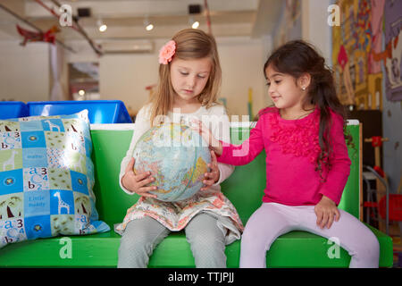 Ragazze guardando al mondo stando seduti sul sedile verde a cura del bambino Foto Stock