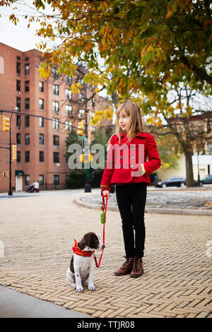 Ragazza con il cane che guarda lontano mentre si sta in piedi sul sentiero Foto Stock