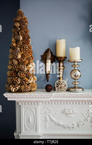 Decorazioni natalizie e candele su mantelpiece Foto Stock