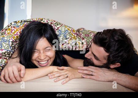 Coppia felice di parlare mentre giaceva sul letto di casa Foto Stock