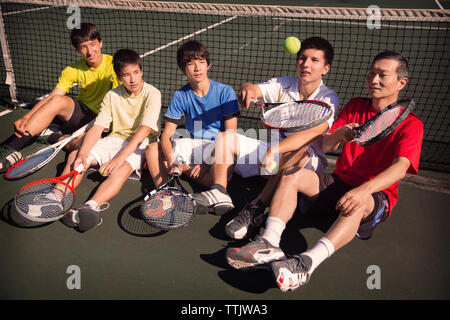 Il giocatore che mostra le abilità di tennis a team mentre poggia contro la net a corte Foto Stock